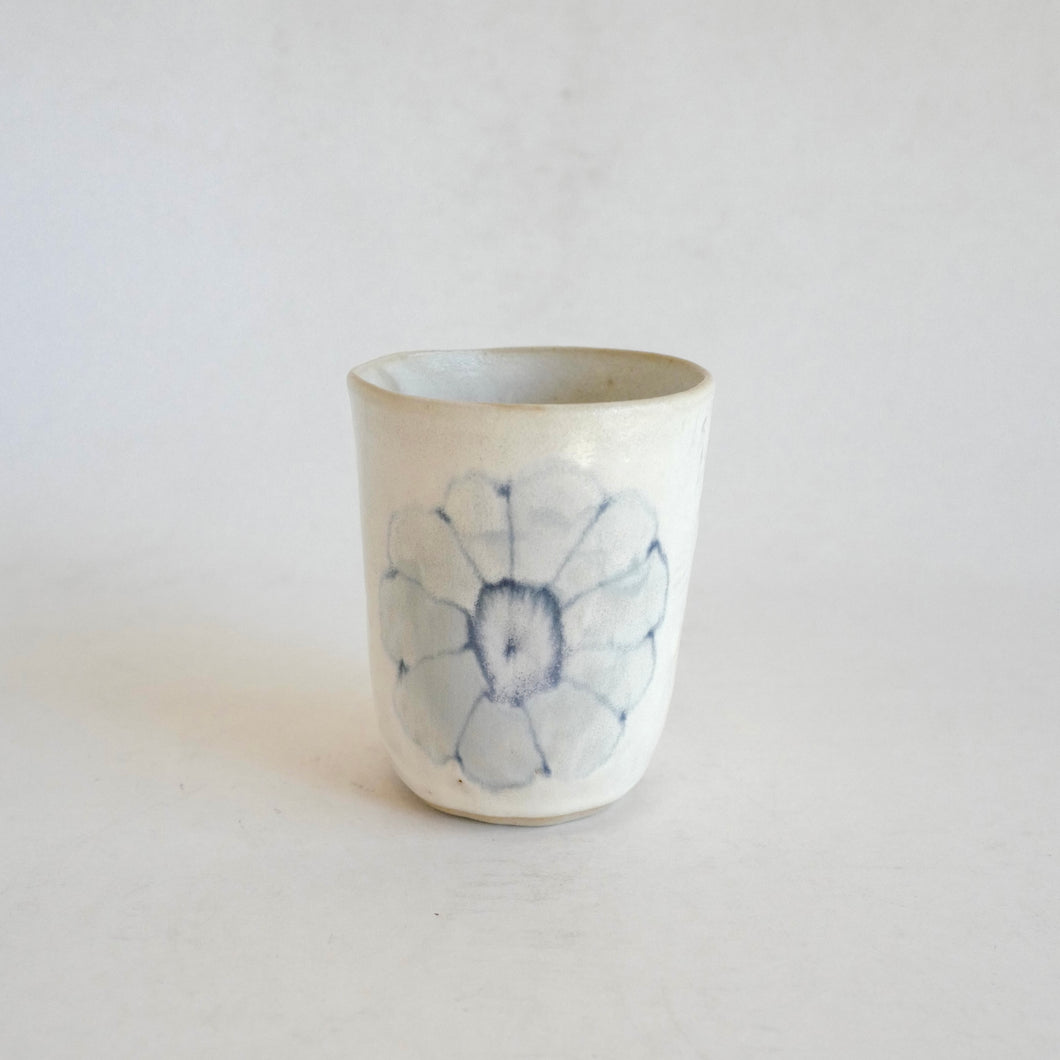 White Tumbler with blue flower pattern on beige background