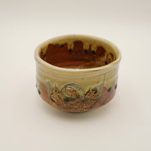 A handmade ceramic bowl with a rustic hand-painted design and a glossy brown and beige glaze, photographed on a neutral light gray background.