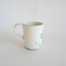 White Mug with blue flower pattern on beige background