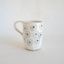White Mug with blue flower pattern on beige background