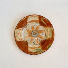 Ceramic plate with decorative brown and beige pattern on a white background