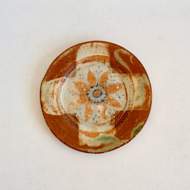 Ceramic plate with decorative brown and beige pattern on a white background