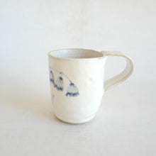 White Mug with blue flower pattern on beige background