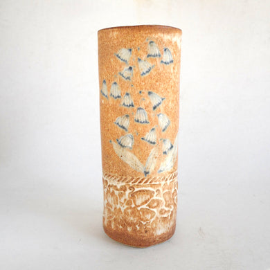 Cylindrical ceramic vase with blue flower design on a white background