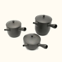 Three black ceramic pots with lids on a white background