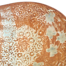 Close-up of a ceramic plate with floral patterns and glaze variations.