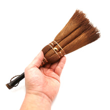 Hand holding a wooden brush with bristle head against a light background