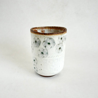 White ceramic cup with floral design on a white background