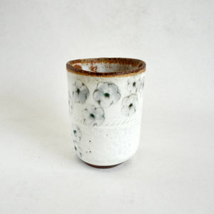 White ceramic cup with floral design on a white background