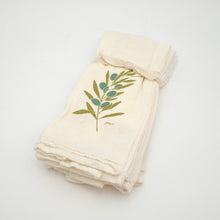 Folded cream-colored towel with green leaf design on a white background