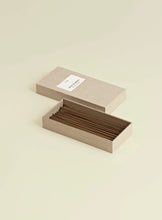 Open box with incense sticks on a beige background