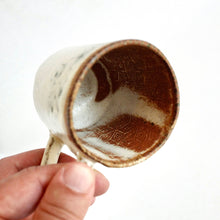 Hand holding a ceramic mug with a textured interior against a white background