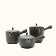 Set of three black ceramic teapots on a white background
