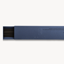 Open incense box showing black incense sticks on white background