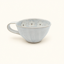 Light blue ceramic cup with floral patterns on a white background