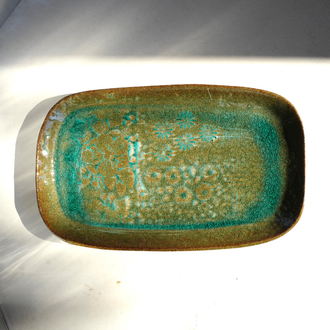 Rectangular ceramic dish with green and brown glaze on a white background