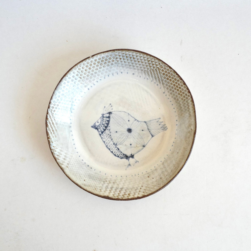 Ceramic plate with textured rim and central design on a white background