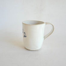 White Mug with blue flower pattern on beige background