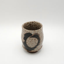 Ceramic cup with speckled texture and black design on a white background