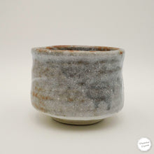 A handmade ceramic tea whisk holder or small bowl with a textured, speckled gray and brown glaze, photographed on a neutral light gray background.