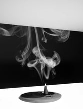 Incense cone with smoke rising against a black background