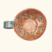 Ceramic mug with speckled glaze and floral on a white background
