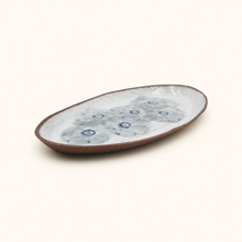 Oval ceramic plate with blue floral pattern on a white background