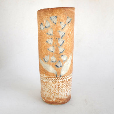 Cylindrical ceramic vase with blue floral design on a white background