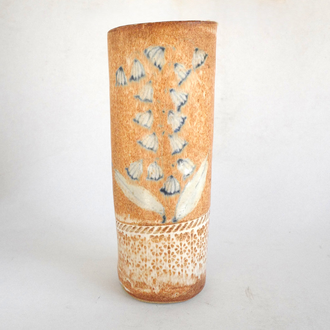 Cylindrical ceramic vase with blue floral design on a white background