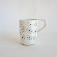 White Mug with blue flower pattern on beige background