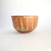 Ceramic bowl with a textured brown and green surface on a white background