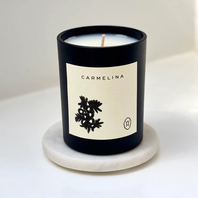 Candle with 'Carmelina' label on a white background