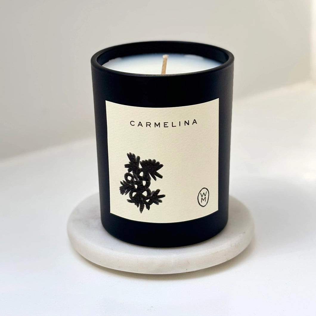 Candle with 'Carmelina' label on a white background