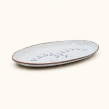 Oval ceramic plate with textured surface on a white background