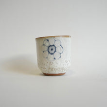 Spako Clay Wide Tumbler single blue flower on white glaze. Foliage texture.