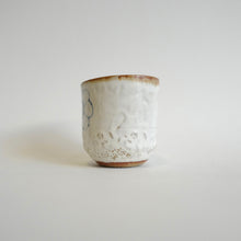 Spako Clay Wide Tumbler single blue flower on white glaze. Foliage texture.