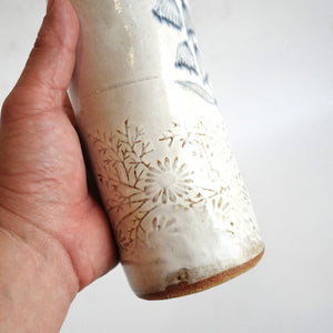 Hand holding a Spako Clay extra Tall Vase blue floral drawing and emboss pattern, white glaze