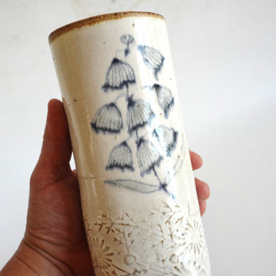 Hand holding a Spako Clay extra Tall Vase blue floral drawing, white glaze