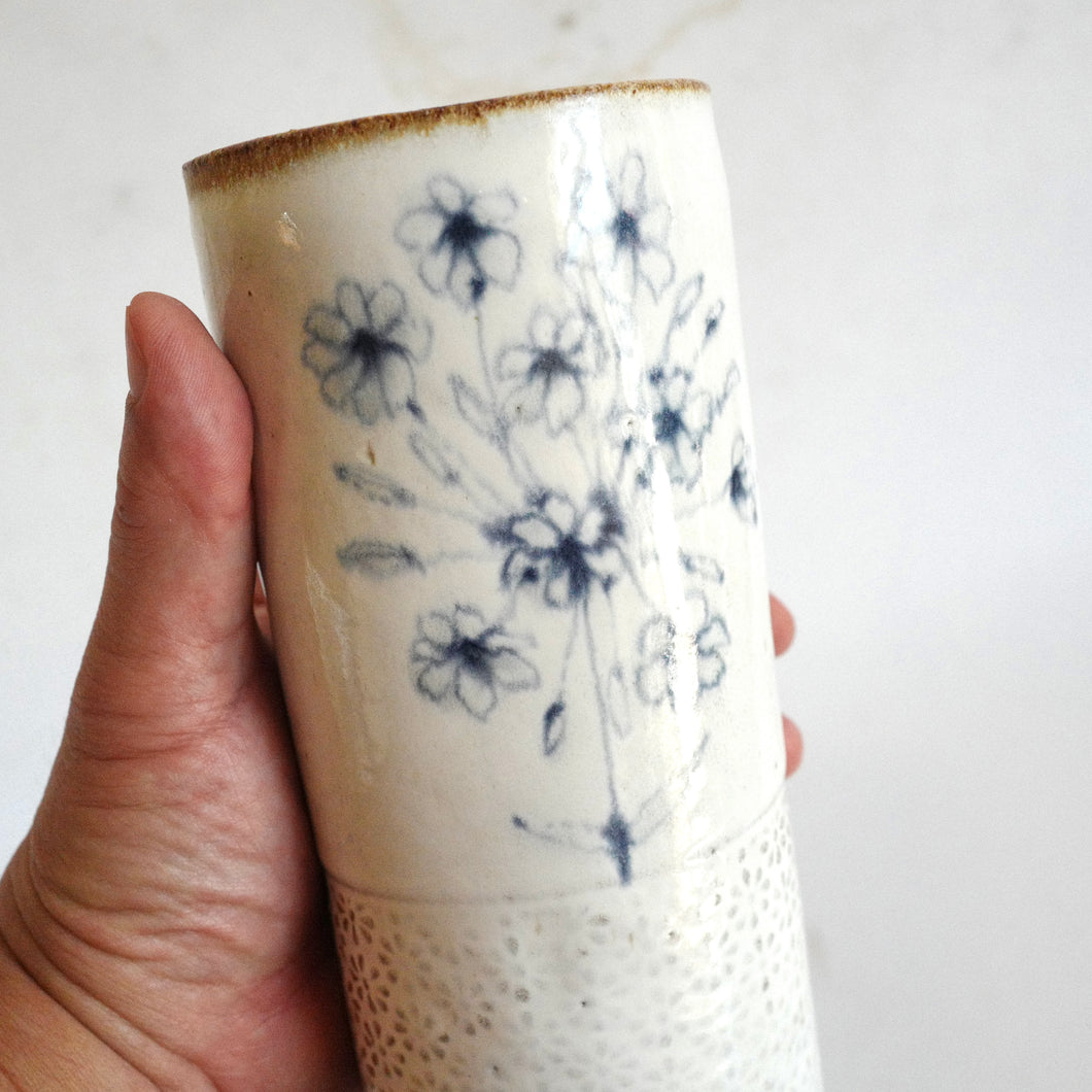 Hand holding a Spako Clay extra Tall Vase blue floral drawing, white glaze