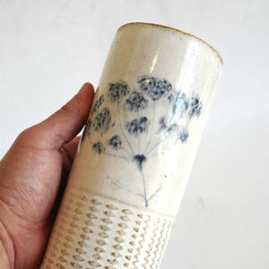 Hand holding a Spako Clay extra Tall Vase blue floral drawing with geometric embossing pattern, white glaze