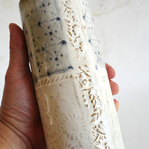 Hand holding Spako Clay extra Tall Vase blue geometric drawing with floral embossing pattern, white glaze