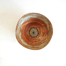 Round ceramic bowl with a unique, multicolored design on a white background