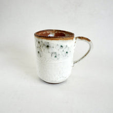 White ceramic mug with brown rim on a light gray background