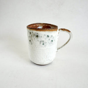 White ceramic mug with brown rim on a light gray background