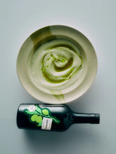 Olive oil bottle laid on a table with a bowl of creamy sauce
