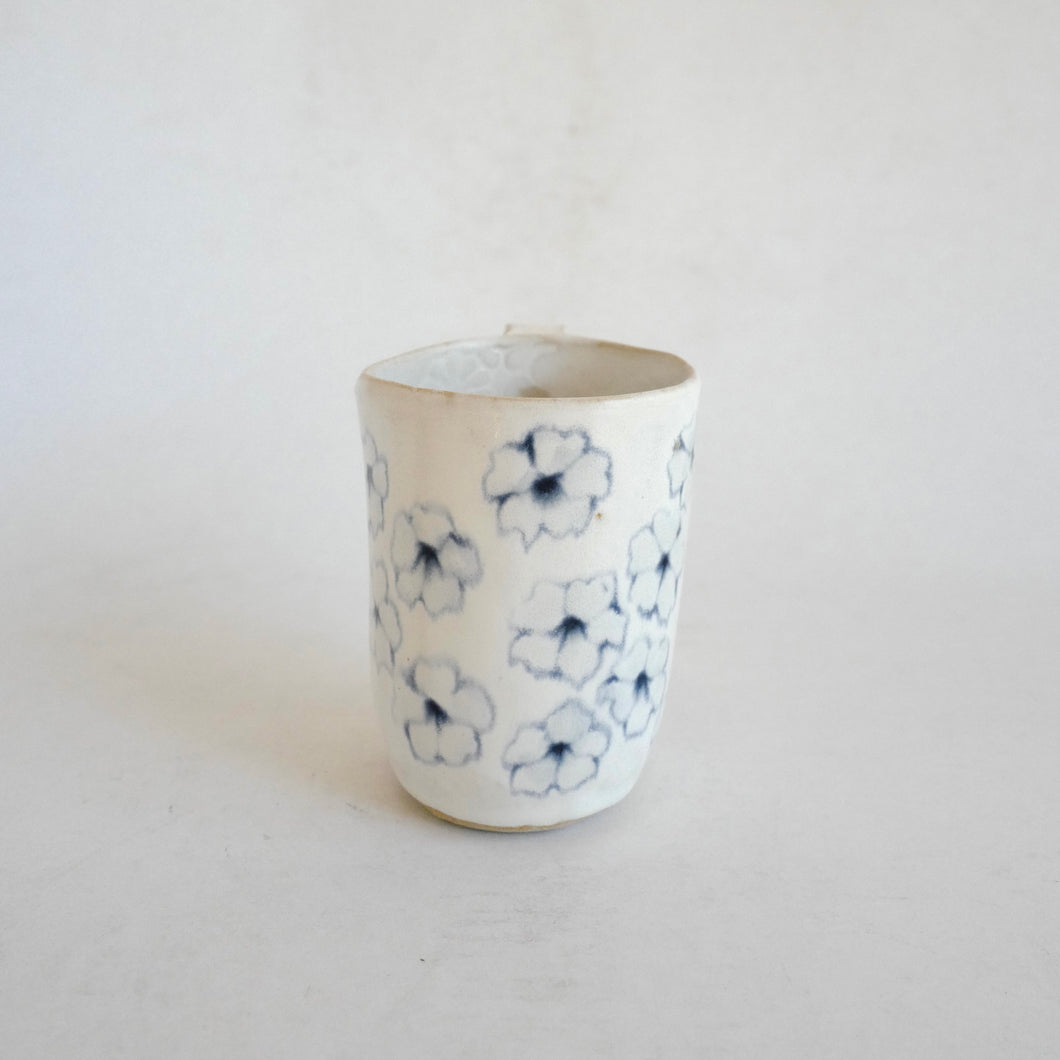 White Mug with blue flower pattern on beige background