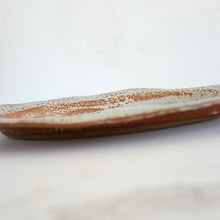 Ceramic plate with brown speckled pattern on a white background