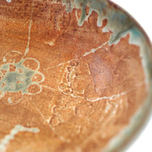 Close-up of a ceramic bowl with brown glaze and white speckles