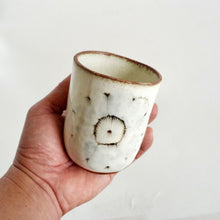 Hand holding Spako Clay Wide Tumbler wildflower drawing, white glaze 