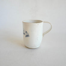 White Mug with blue flower pattern on beige background